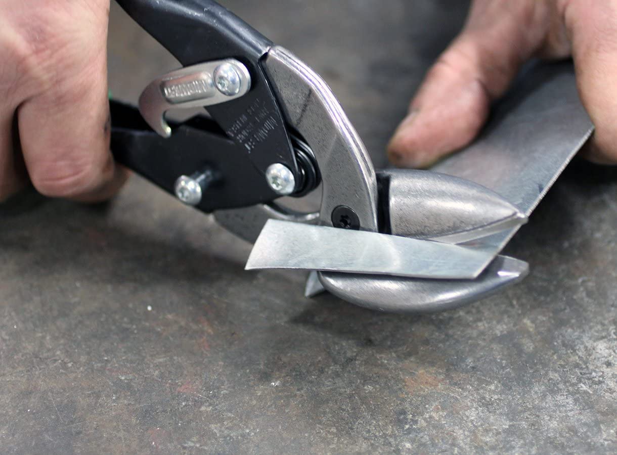 A pair of tin snips cutting a small square of sheet metal.