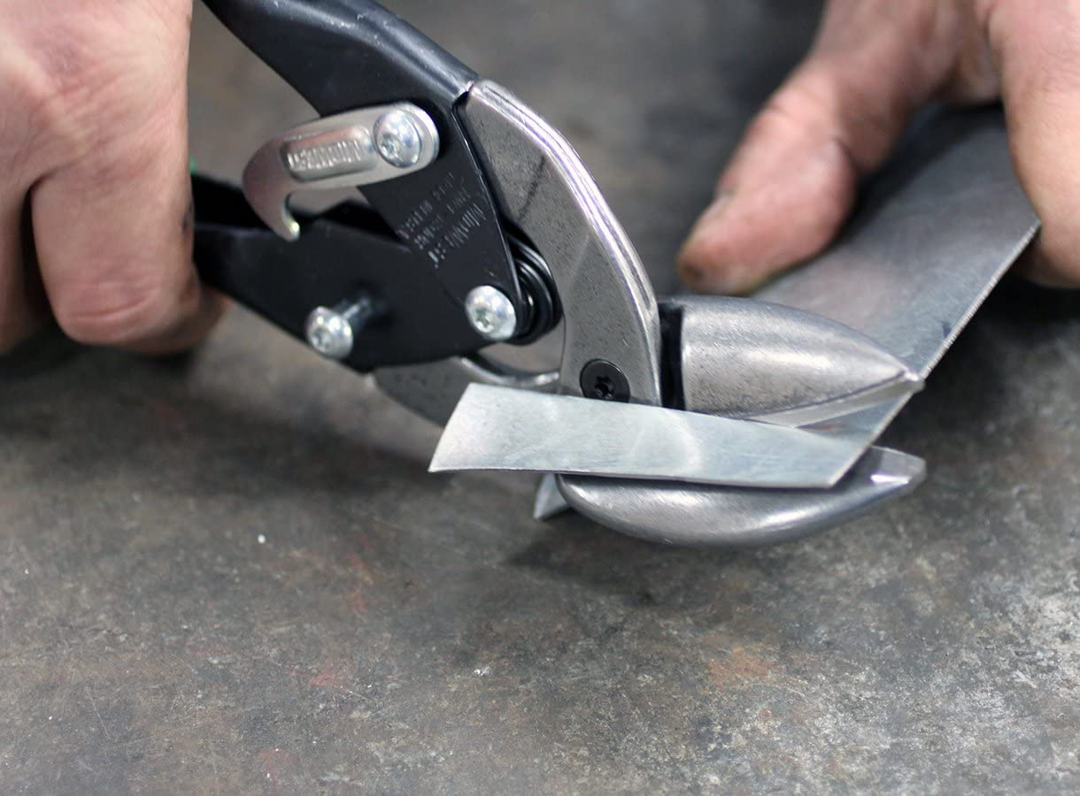 A pair of tin snips cutting a small square of sheet metal. 